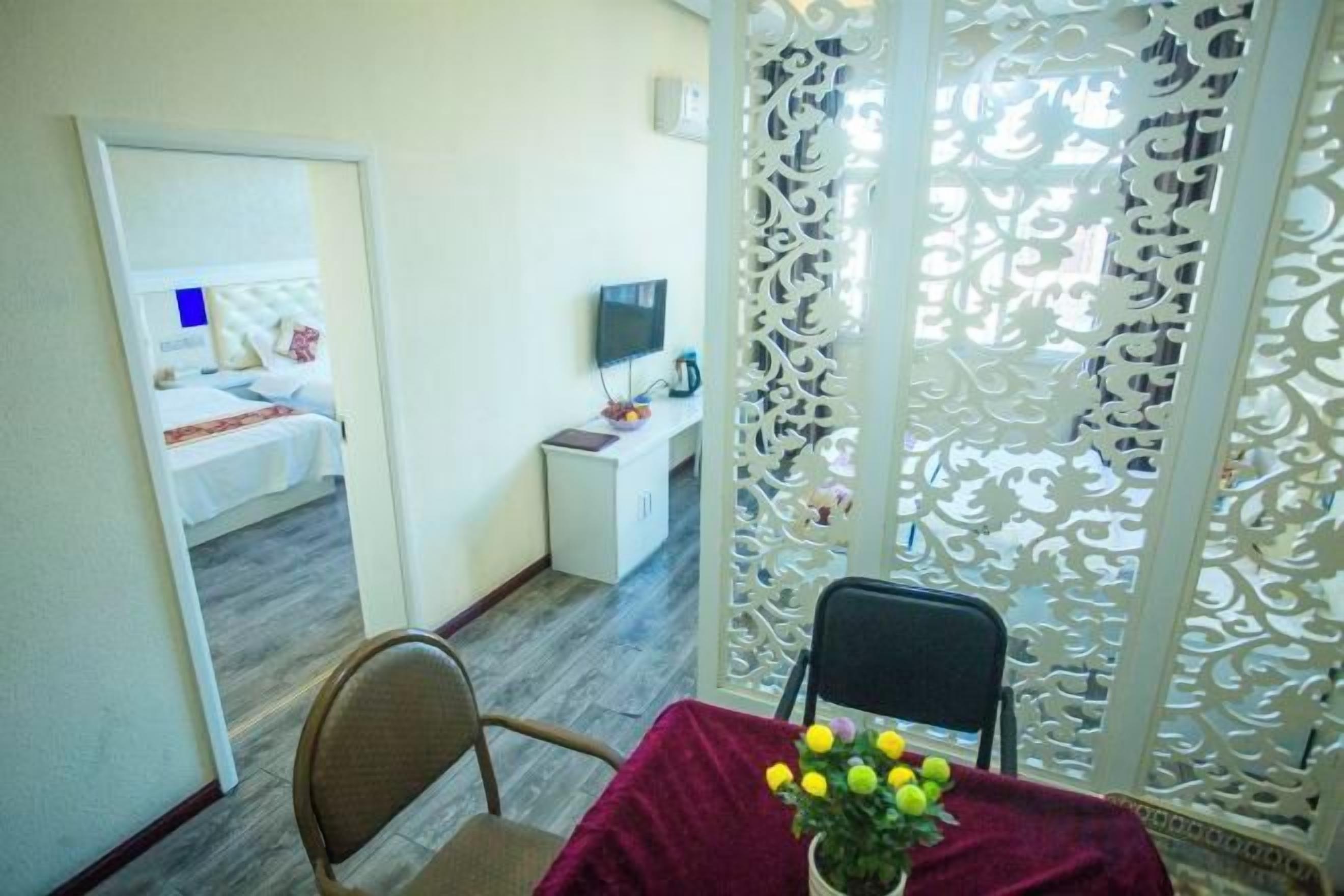 Habitación de hotel con cama, televisión, escritorio y zona de comedor con mesa y sillas.