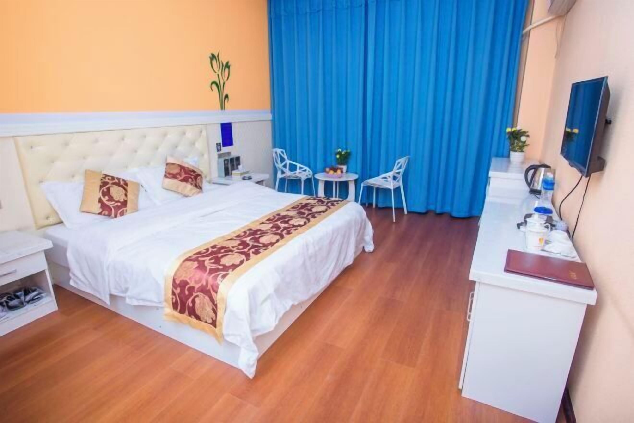 Una habitación de hotel con cama, escritorio, dos sillas, una mesita y televisor.