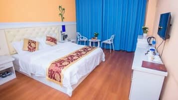 Una habitación de hotel con cama, escritorio, dos sillas, una mesita y televisor.