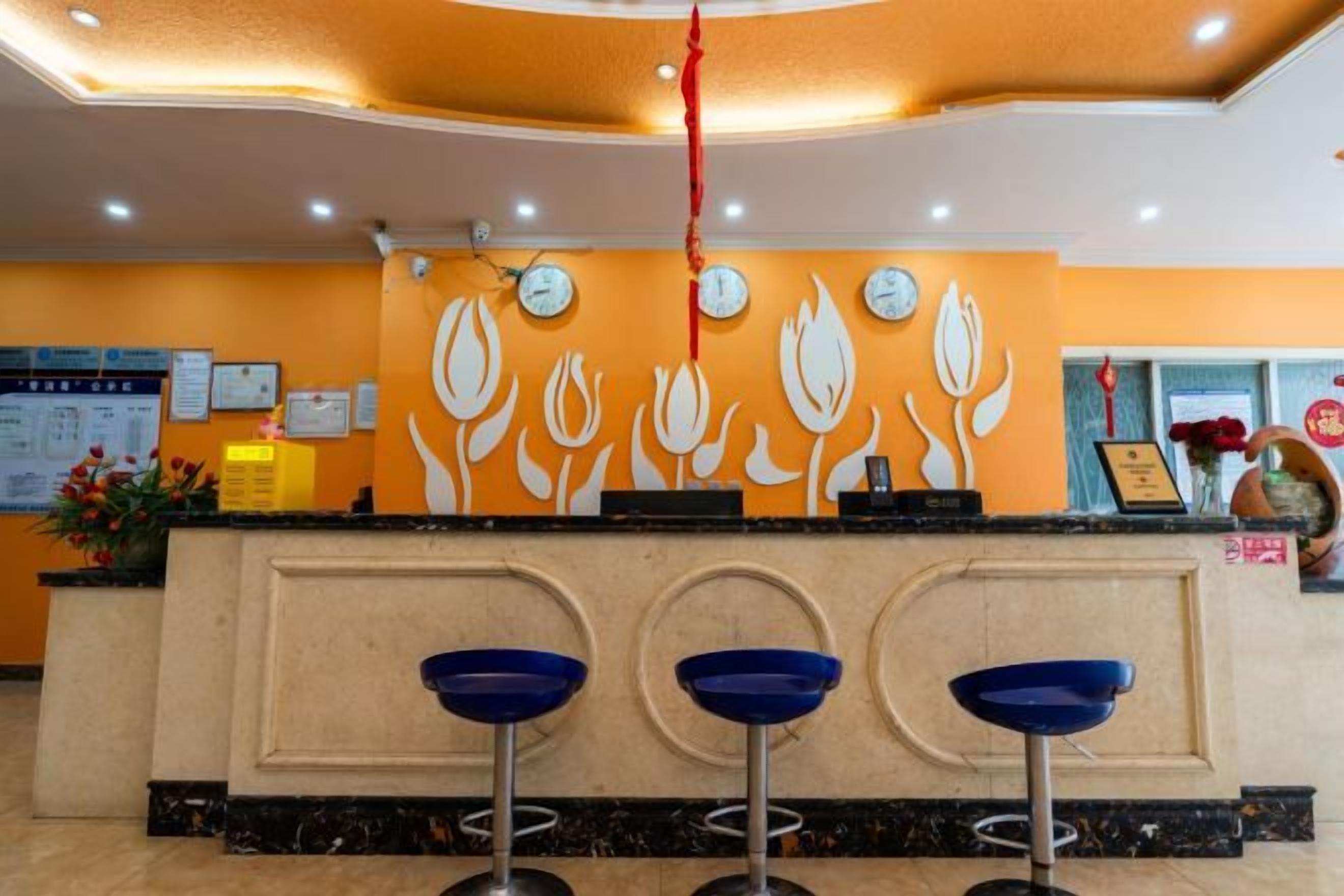 A reception area with a counter, three blue bar stools, and a wall with a floral design.