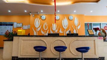 A reception area with a counter, three blue bar stools, and a wall with a floral design.