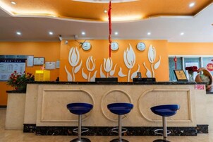 Un área de recepción con un mostrador, tres taburetes azules y una pared con diseño floral.