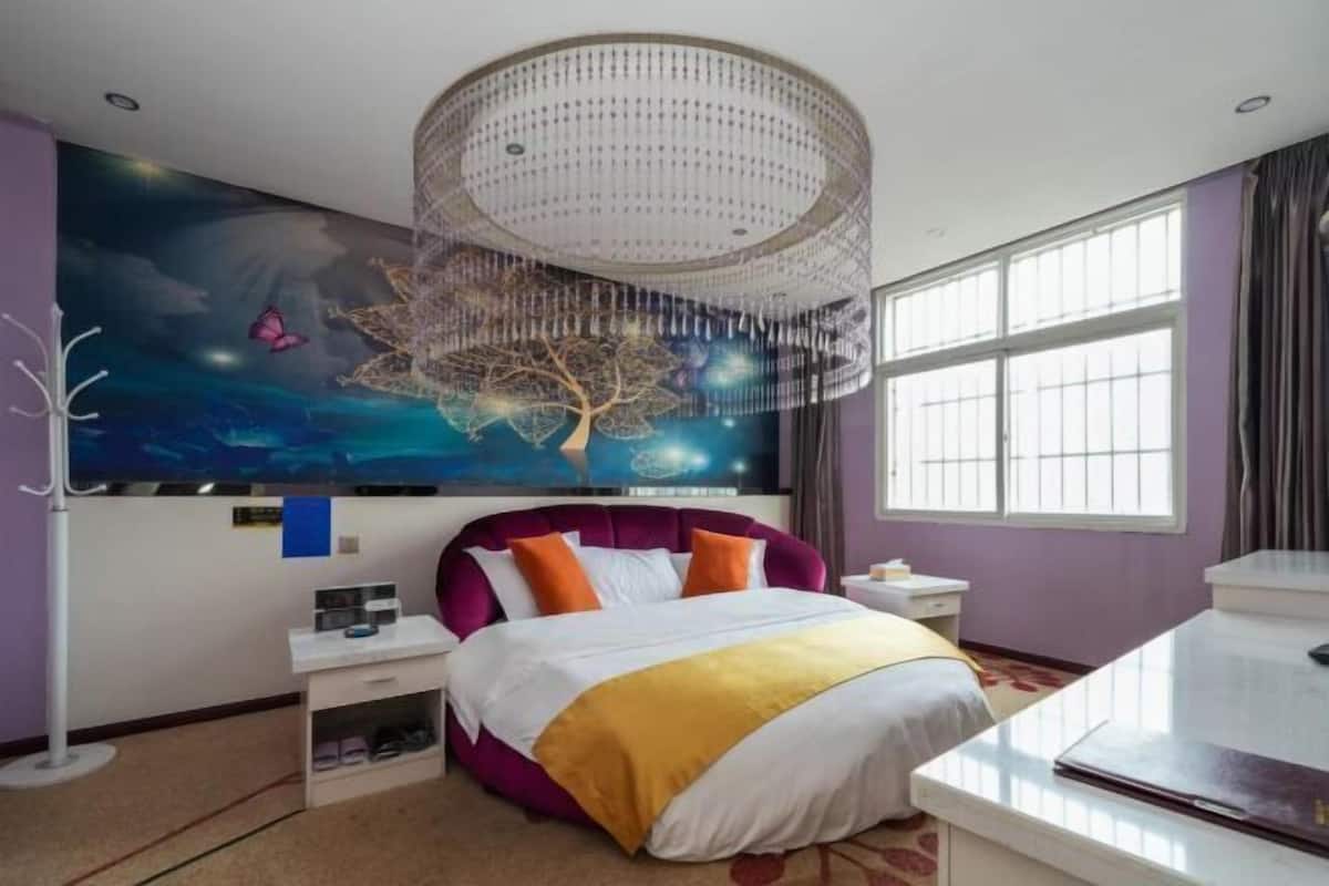 Un dormitorio con una cama grande, una araña, un mural en la pared y una ventana.