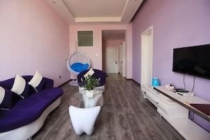 A modern living room with a sofa, a hanging chair, a coffee table, and a flat-screen TV. - Tulip Fashion Hotel (Zhuquan Road Branch) (Zhaotong)