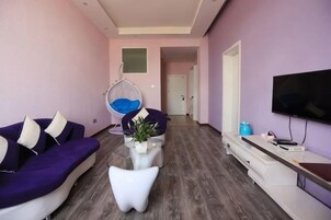 Una sala moderna con sofá, una silla colgante, una mesa de centro y un televisor de pantalla plana.