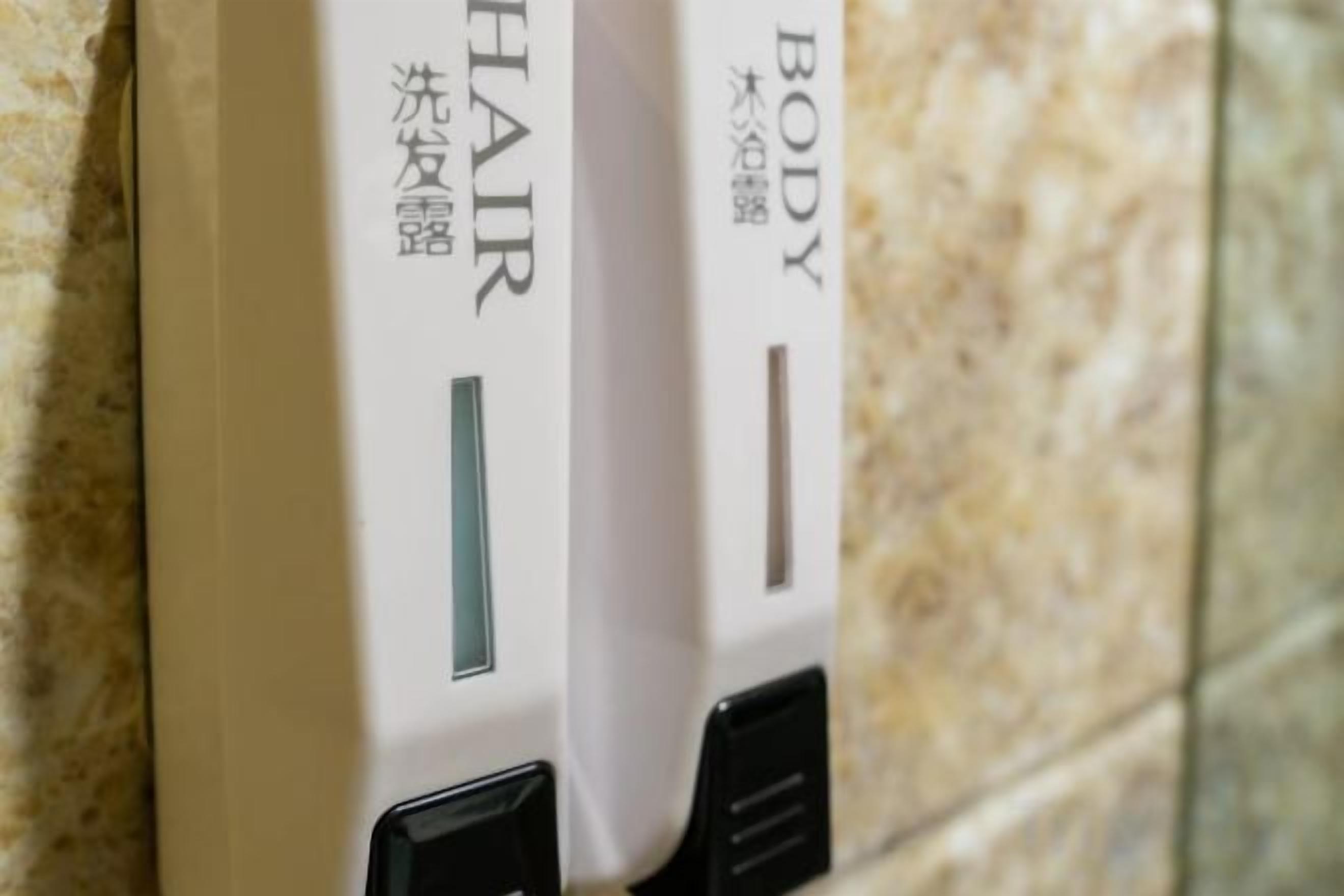 A close-up of a wall-mounted device with the words 'HAIR' and 'BODY' visible, indicating it might be a hair and body care product dispenser.