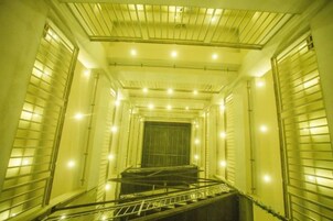 Una escalera estrecha y cerrada con barandillas metálicas y una serie de luces a lo largo del techo.
