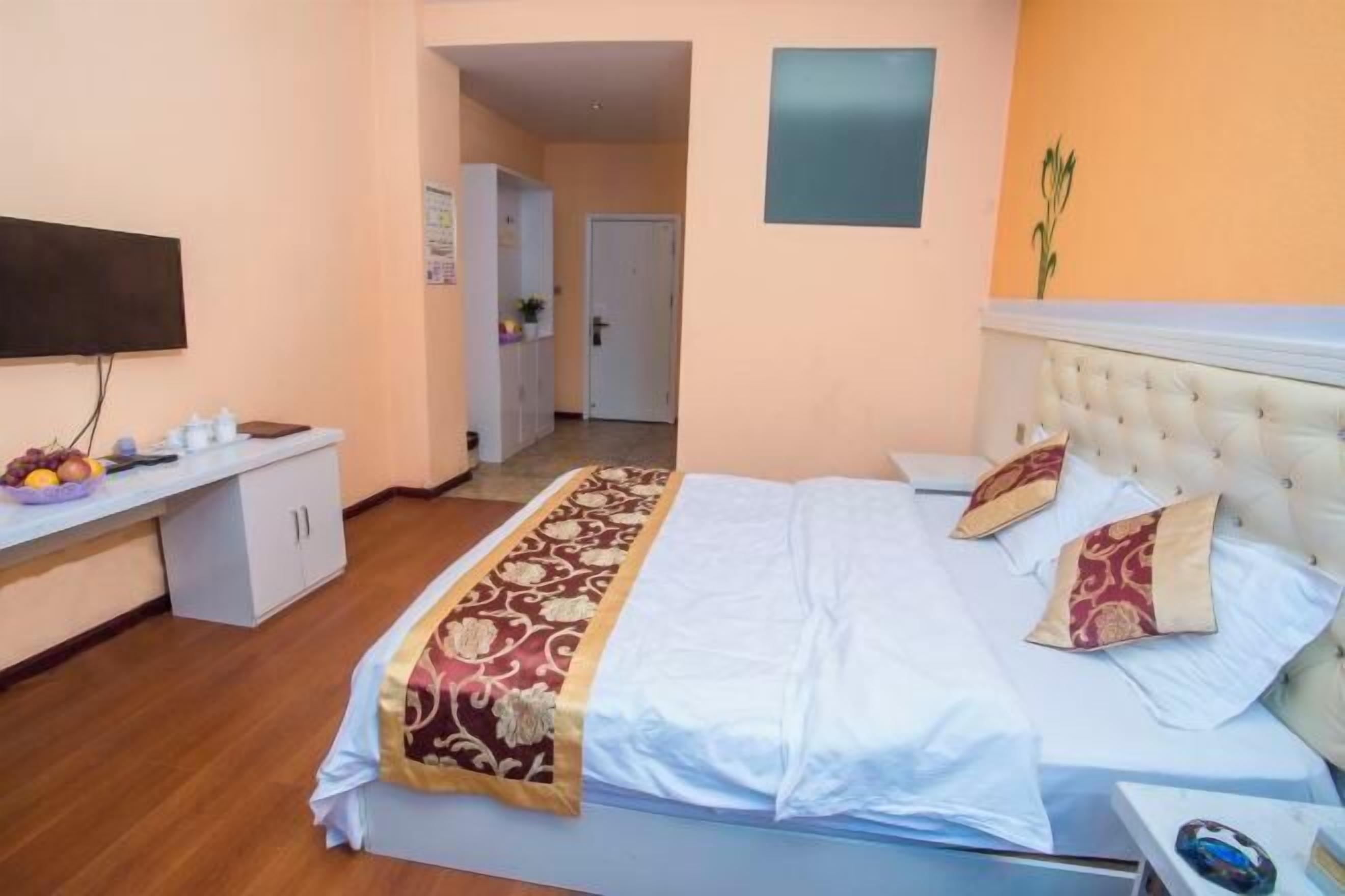 Un dormitorio con cama, mesita de noche, televisor y puerta que da a otra habitación.