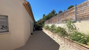 Un sentiero stretto che conduce a un edificio con una finestra e un faretto a parete.