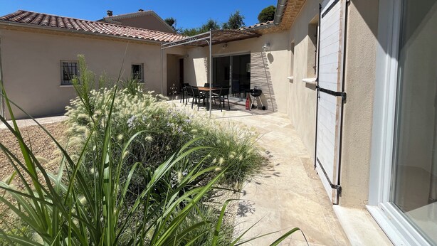 Una zona patio con tavolo e sedie, un barbecue e un'area salotto coperta.