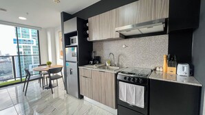 A modern kitchen with a built-in oven, microwave, and sink. There is a dining area with a table and chairs.