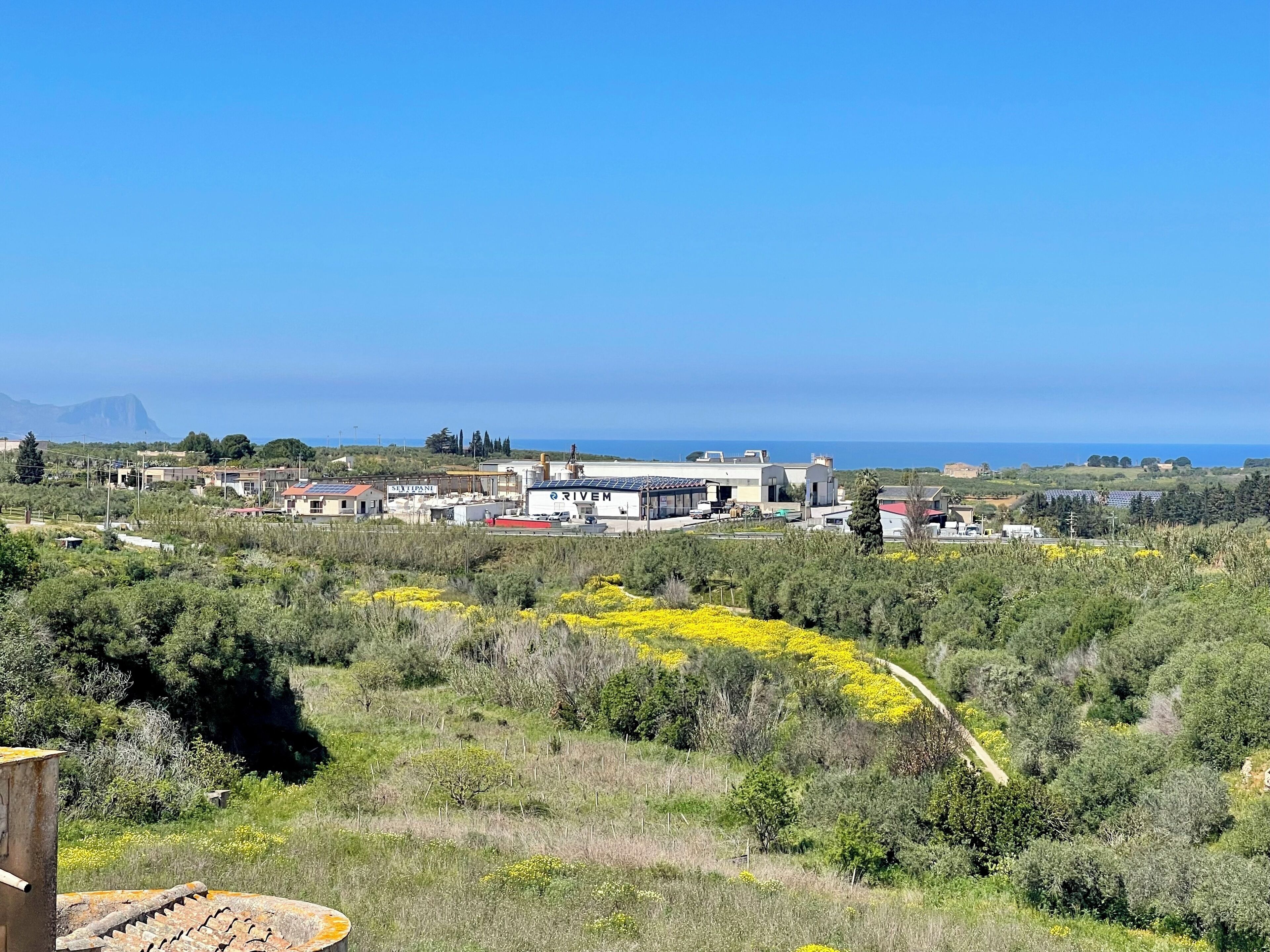 A coastal industrial area with buildings, solar panels, and a clear view of the sea.