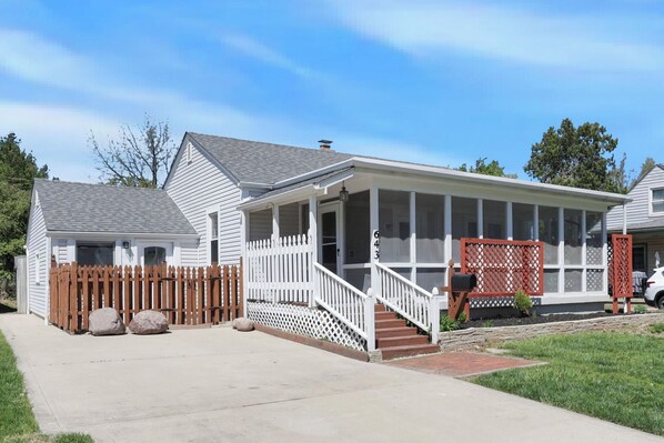 A single-story house with a porch, a wooden fence, and a mailbox.