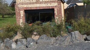 A brick building with a garage entrance, surrounded by a gravel driveway and a wooden fence. - l'épi dort (Saint Maclou la Briere)