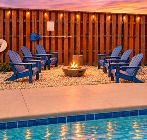 A poolside area with Adirondack chairs, a fire pit, and a wooden fence. - Lion of the Beach. Heated Pool, 4 bedrooms,6beds, 3.5baths, Games, Pet friendly (Panama City Beach)