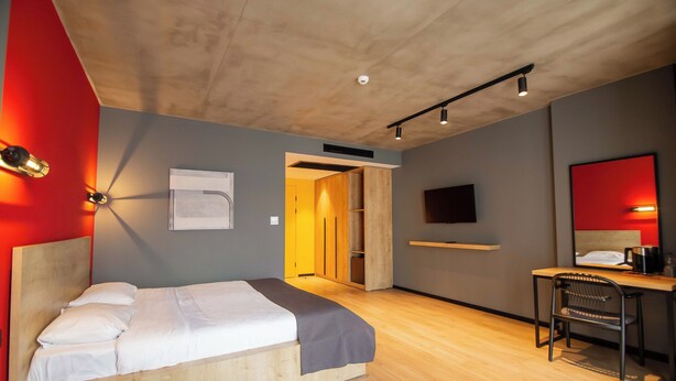 Una moderna camera d'albergo con un letto, una scrivania, una sedia e una televisione.