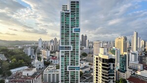 Un moderno edificio de gran altura con un diseño arquitectónico único, rodeado de otros rascacielos en un paisaje urbano.