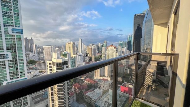 Vista panorámica de la ciudad desde un balcón con barandilla de vidrio.