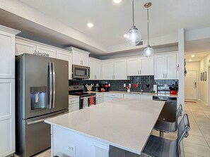 A modern kitchen with a large island, stainless steel appliances, and pendant lighting. - Storey Lake Spacious 2-BR Condo, Resort Amenities (Kissimmee)