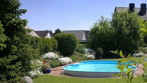 A round above-ground pool surrounded by a well-maintained lawn and various plants. - Your vacation address in the beautiful, hilly Teutoburg Forest (Extertal)