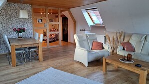 A modern living room with a dining area, wooden ceiling, stone wall, and a skylight. - Your vacation address in the beautiful, hilly Teutoburg Forest (Extertal)