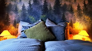 A bedroom with a forest-themed wall mural, a bed with multiple pillows, and two bedside lamps. - Your vacation address in the beautiful, hilly Teutoburg Forest (Extertal)