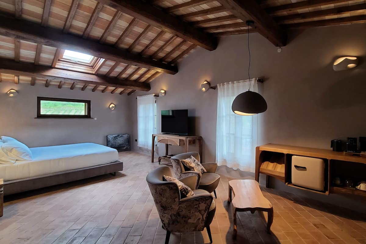 Um quarto aconchegante com uma cama, uma TV, uma mesa de jantar e um sofá.