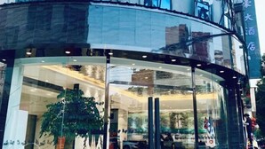 Ein Hotel Eingang mit Glasfassade, einem großen Topfpflanzen und einem Spiegelbild des Innenraums.