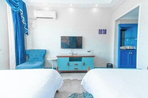 A hotel room with two beds, a television, a blue cabinet, and a blue door.
