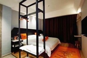 A hotel room with a bunk bed, a desk with a chair, a small table, and a wardrobe.