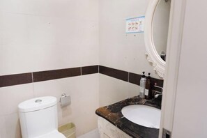 A bathroom with a toilet, sink, and mirror. - Lihao Hotel (Zhaotong Ancient City) (Zhaotong)