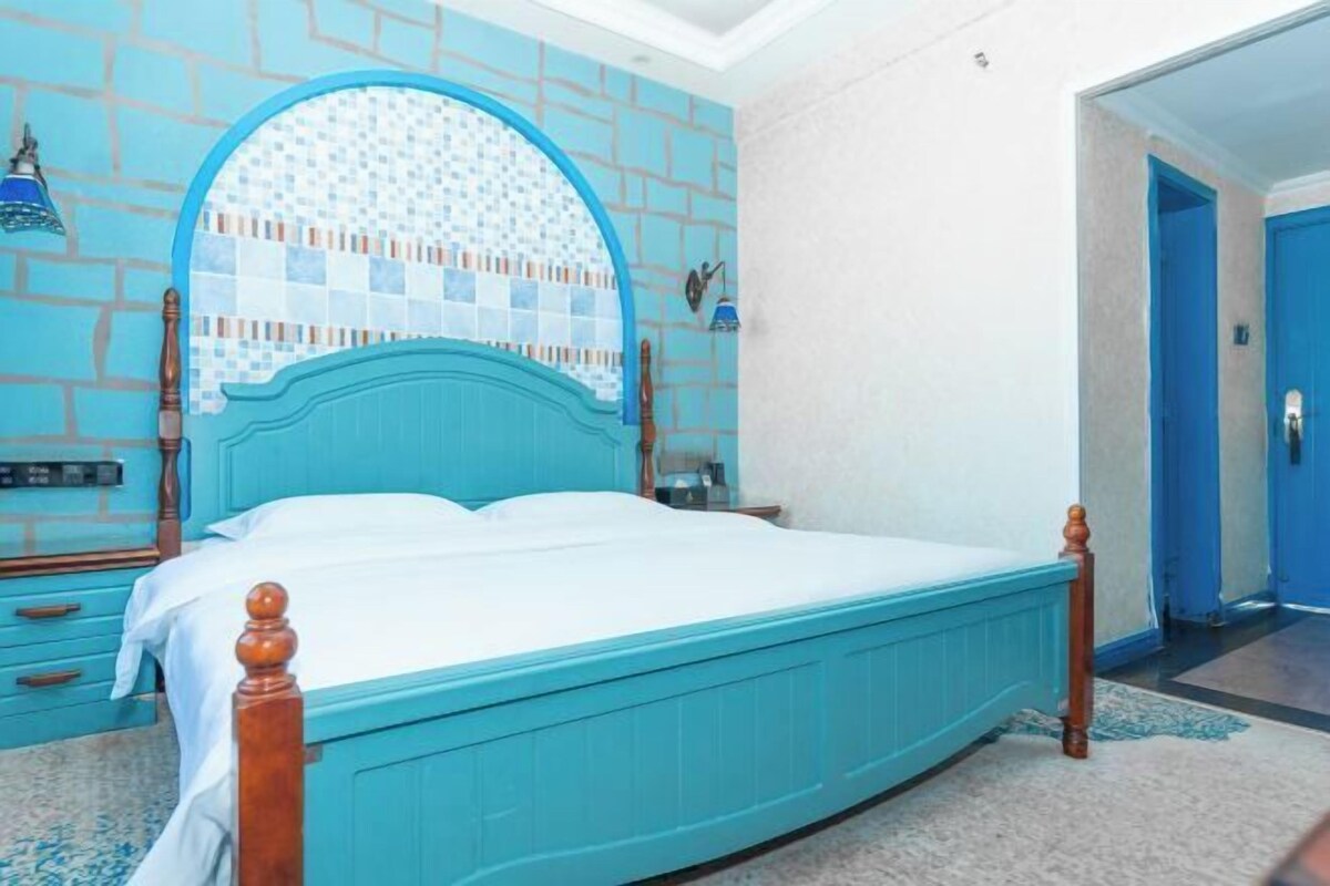 A room with a turquoise bed, a tiled wall, and a blue door.