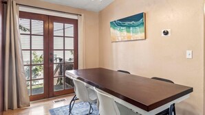 A dining area with a wooden table and chairs, a ceiling fan, a painting on the wall, and a sliding glass door leading to an outdoor area. - Charming Mountain Retreat with Enclosed Backyard and Artistic Flair (Millcreek)