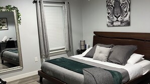 A modern bedroom with a large bed, a ceiling fan, a tiger artwork, and a window with curtains.