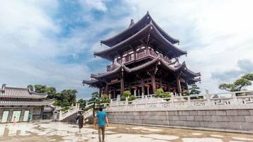 Un pavillon chinois traditionnel doté d’une toiture à plusieurs niveaux, entouré d’un mur de pierre et dont le sol est humide.
