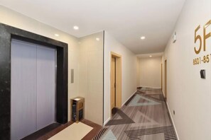 A hotel corridor with a carpeted floor, a door with a digital display, and a wall with a number. - Dong'an Business Hotel (Guilin University of Technology Pingfeng Campus Branch) (Guilin)