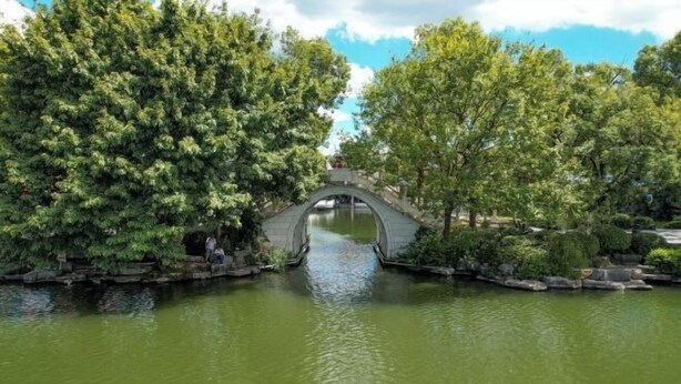 Un pont de pedra sobre un tram d'aigua tranquil·la, envoltat de vegetació exuberant.