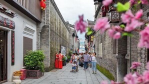 Un carrer estret amb arquitectura tradicional, una multitud de persones i un nen jugant.