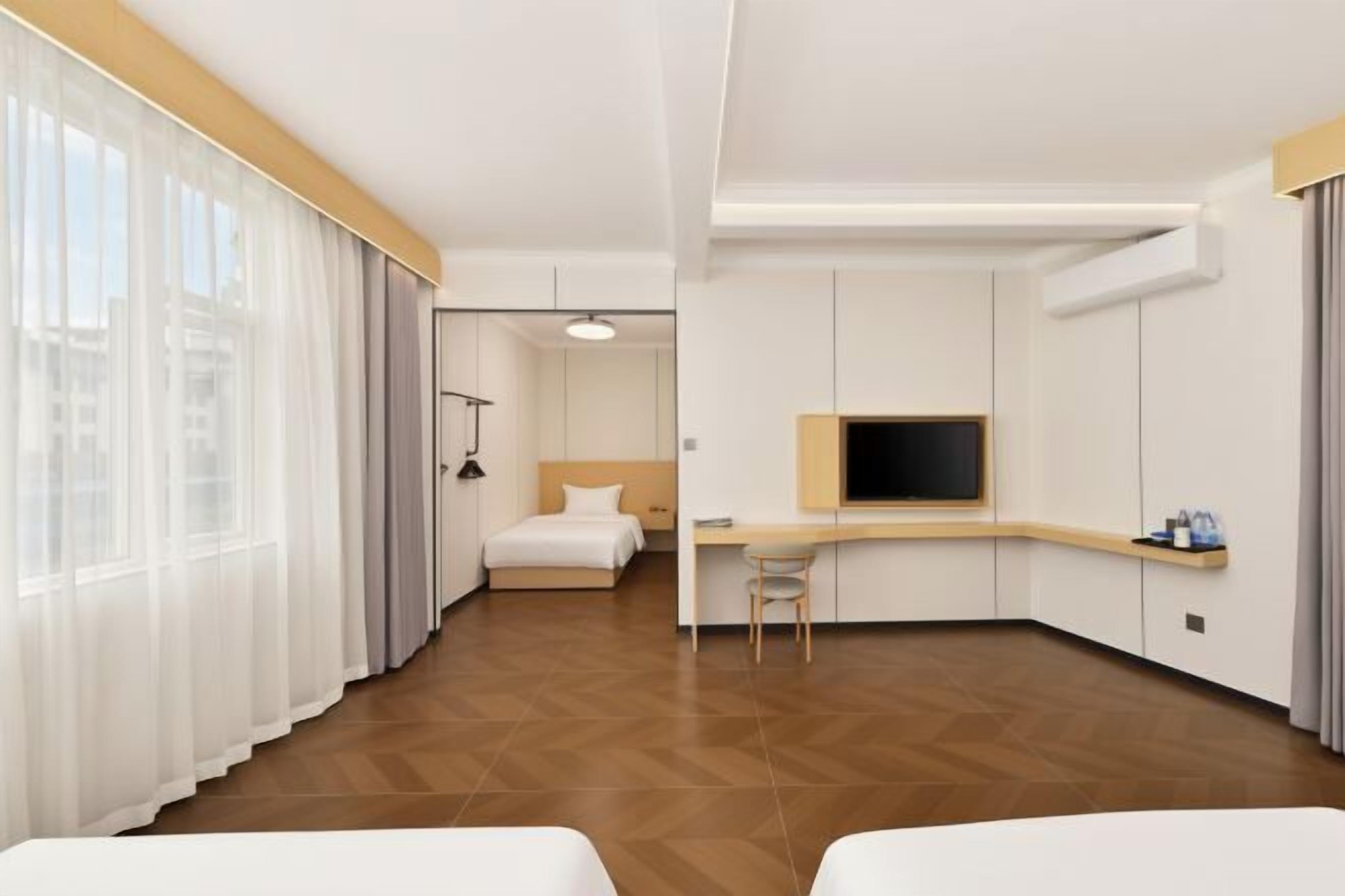 Habitación de hotel con cama, escritorio, silla y televisor.
