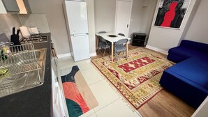 A compact living space with a kitchenette, a dining area, and a blue sofa. - The Walthamstow Lodge (London)