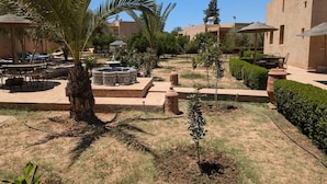 A courtyard with outdoor seating, palm trees, and a water feature. - Riad dar chenguiti (Taroudant)