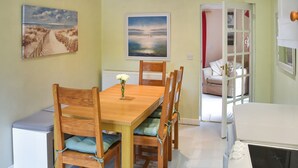 A dining area with a wooden table and chairs, a vase of flowers, and two paintings on the walls. - Idyllic views, yet close to amenities and places of interest to explore. (Flordon)