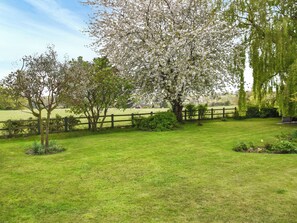 A grassy field with a wooden fence and trees with white blossoms. - Idyllic views, yet close to amenities and places of interest to explore. (Flordon)