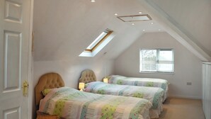 A bedroom with two beds, a skylight, a window, and a small wicker chest. - Idyllic views, yet close to amenities and places of interest to explore. (Flordon)