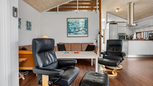 A modern interior with a wooden ceiling, a dining table, black leather chairs, a brown leather sofa, and a kitchen in the background. - Stunning home in ålbæk with sauna (Ålbæk)