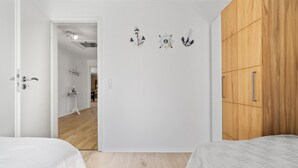A bedroom with a wooden wardrobe, a white door, and a hallway leading to a kitchen. - 3 bedroom nice home in Ulfborg (Ulfborg)