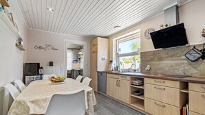 A modern kitchen with a dining area, wooden cabinets, and a window overlooking a garden. - 3 bedroom nice home in Ulfborg (Ulfborg)