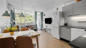 Eine moderne Küche mit weißen Schränken, einem Geschirrspüler von Bosch sowie einem Essbereich mit Holztisch und Stühlen.