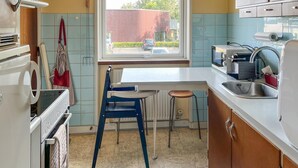 Une cuisine de taille réduite, dotée d’une fenêtre, d’un évier et d’appareils électroménagers de base.