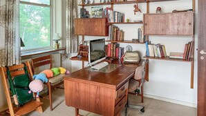 Une salle d’étude équipée d’un bureau en bois, d’un ordinateur, de bibliothèques et d’une chaise agrémentée de coussins colorés.